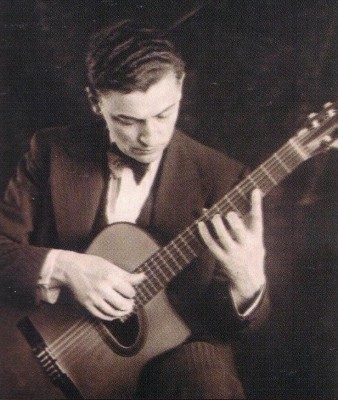 Maccaferri in abito gessato seduto che suona una delle sue chitarre